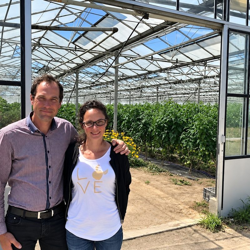 Gildas et Stéphanie, souriants, devant leur serre de tomates
